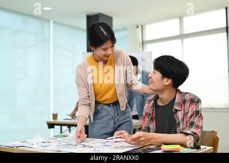 Due giovani designer che si occupano di brainstorming e discutono per il progetto di progettazione di software applicativi mobili in ufficio Foto Stock