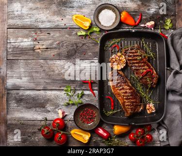 Bistecca di striploin alla griglia con spezie ed erbe sulla teglia di ferro. La bistecca di strip, chiamata anche striscia di New York. Foto Stock