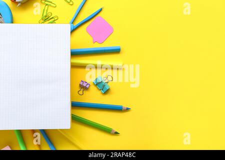 Cornice realizzata in cancelleria diversa con blocco note vuoto su sfondo giallo Foto Stock