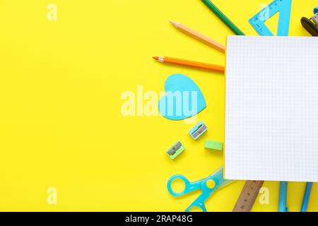 Cornice realizzata in cancelleria diversa con blocco note vuoto su sfondo giallo Foto Stock