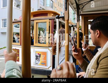 A bordo della funivia di San Francisco che passa tra loro piena di turisti Powell Street San Francisco California USA Foto Stock