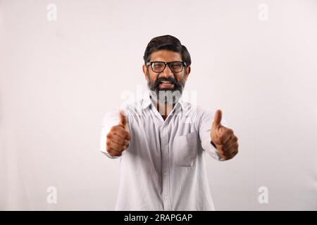 Ritratto di un uomo barbuto indiano che indossa una camicia. Espressioni funky senso di realizzazione e realizzazione. Pollice in alto. Strategia vincente. Foto Stock