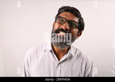 Ritratto di un uomo barbuto indiano che indossa una camicia. Espressioni funky tristi e sgradevoli, piene di rabbia e aggressività. Foto Stock