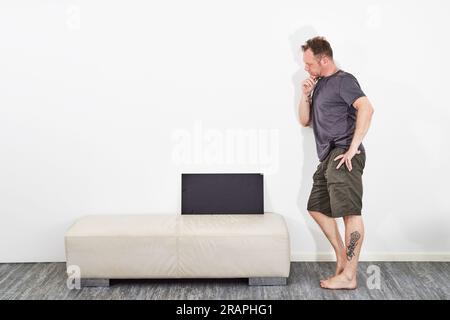 Uomo in pantaloncini con cartello nero a piedi nudi Foto Stock