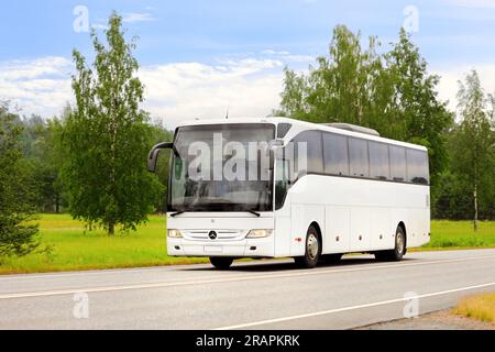 Autobus Mercedes-Benz Tourismo bianco a velocità su strada il giorno d'estate, cielo blu e nuvole, spazio per le copie per il testo. Salo, Finlandia. 22 giugno 2023. Foto Stock