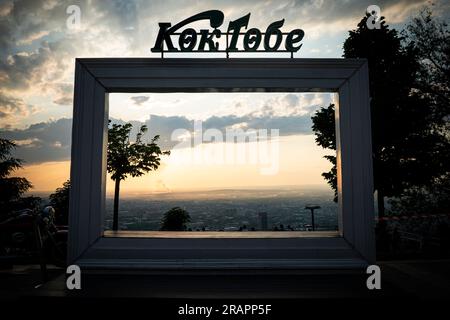 Incredibile vista panoramica del tramonto sulla città di Almaty dalla collina di Kok-Tobe in una nuvolosa serata. Il miglior punto panoramico nella capitale meridionale del Kazakistan. Traduzione da Ka Foto Stock