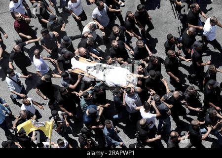 Jenin, territori palestinesi. 5 luglio 2023. I luttuosi assistono a una processione funebre mentre trasportano il corpo di un palestinese ucciso dalle forze israeliane in Cisgiordania. Nove persone sono state uccise nel più grande schieramento israeliano in Cisgiordania negli ultimi 20 anni, mentre migliaia si sono riunite a Jenin per i loro funerali mercoledì. Credito: Ayman Nobani/dpa - ATTENZIONE: Contenuto grafico/dpa/Alamy Live News Foto Stock