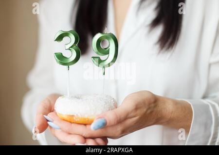 donna che tiene una torta con le candele numero 39. Foto Stock
