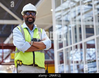 Ritratto, architetto e uomo nero con le braccia incrociate, sorridere o felice per la costruzione. Ingegnere africano, occhiali e appaltatore sicuro di sé, lavoratore o. Foto Stock