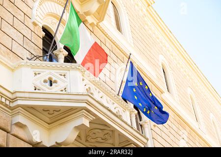 La bandiera italiana e la bandiera europea sventolano sul balcone in stile barocco di un edificio istituzionale nella città di Lecce. Foto Stock