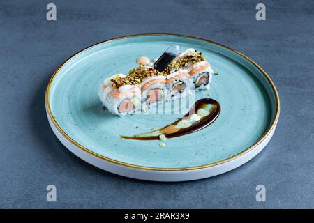 Ristorante sushi, Uramaki Salmon Roll servito su un piatto tondo turchese. Foto Stock