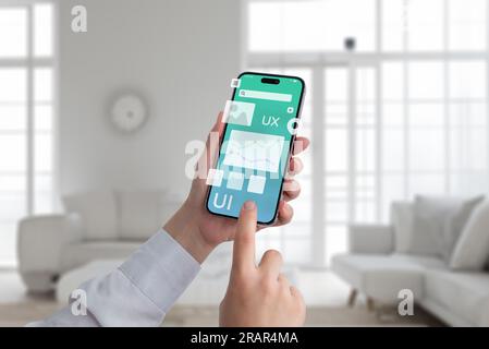 Informazioni sull'interfaccia utente. Smartphone in mano con elementi di design per app volanti Foto Stock