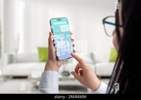 Interfaccia utente e app di concetto Experience su smartphone in mani femminili. Design pulito con il concetto di moduli app volanti Foto Stock