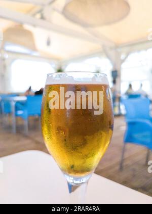 Calice di birra in vetro sulla terrazza sulla spiaggia. Sfondo spagnolo chiringuito Foto Stock