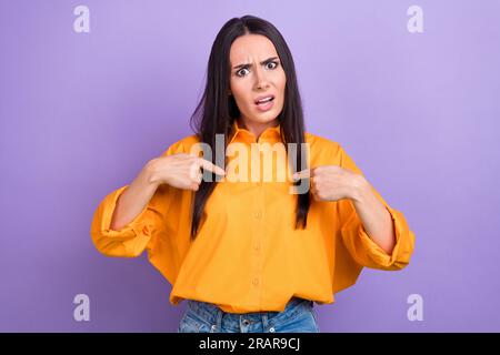 Foto di una ragazza infelice e arrabbiata con una camicia gialla dai capelli dritti che si rivolge a se stessa isolata su sfondo di colore viola Foto Stock