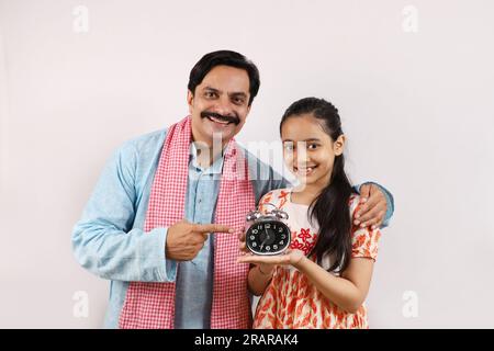 Padre rurale indiano educando e raccontando a sua figlia adolescente l'importanza del tempo e della vita disciplinata. Foto Stock