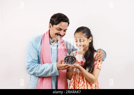 Padre rurale indiano educando e raccontando a sua figlia adolescente l'importanza del tempo e della vita disciplinata. Foto Stock