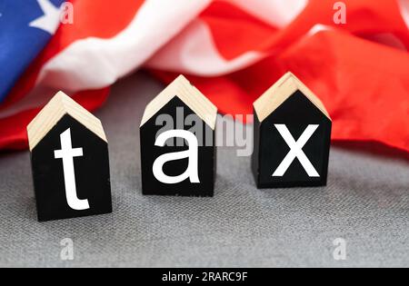 Vista dall'alto dei cubi di legno con TASSA DI testo sulle banconote in dollari americani sulla bandiera americana. Concetto di TASSE e IVA Foto Stock