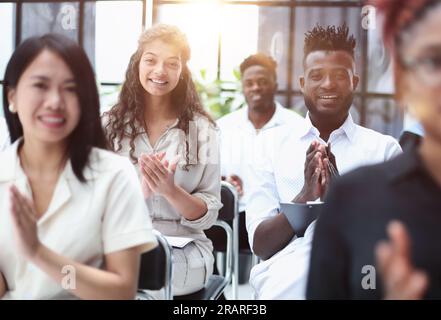 donna d'affari applaudente durante il seminario vicino ai colleghi interrazziali Foto Stock