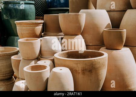 Una varietà di vasi di fiori in terracotta impilati vuoti in diverse dimensioni e forme al centro del giardino Foto Stock