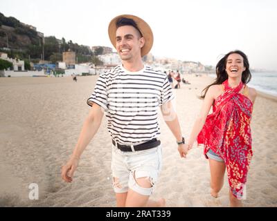 Coppia che corre sulla spiaggia in estate si diverte Foto Stock
