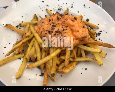 patatine fritte a strisce con salsa brava all'aglio e prezzemolo su piatto di ceramica bianca Foto Stock