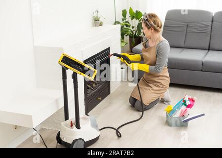 servizio di pulizia professionale. donna in uniforme e guanti spugna lava le finestre panoramiche nel cottage. lavaggio bagno turco e raschietto Foto Stock