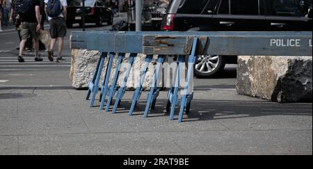 barricate della polizia impilate su un marciapiede vicino a un incrocio (auto e persone che passano) new york city, new york (sfilata, protesta, fiera di strada, Foto Stock