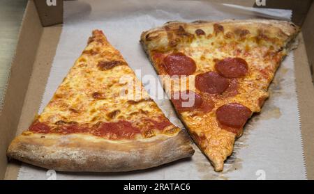 pizzeria di new york con peperoni, fetta di pizzeria nyc con fiocchi di peperoncino rosso schiacciato su carta pergamena grassa e scatola di cartone Foto Stock