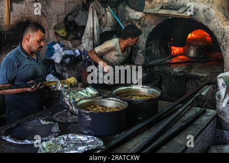 Na'im Sharab, un palestinese di 70 anni, possiede il forno primitivo più antico ereditato dai suoi antenati 130 anni fa. Lui, i suoi figli e nipoti lavorano nel forno nella città di Gaza. Sharab dice che lavorano ogni mattina per preparare il forno, che funziona su legna e olio bruciato acquistato da negozi che sostituiscono gli oli per le auto. Con la crisi dell'elettricità e del gas, alcune persone si sono abituate a inviare pane, caffè e pentole al forno, dove la maggior parte delle pentole da cucina viene prodotta durante l'Eid al-Adha a causa della disponibilità di carne in grandi quantità. Palestina. Foto Stock