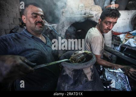 Na'im Sharab, un palestinese di 70 anni, possiede il forno primitivo più antico ereditato dai suoi antenati 130 anni fa. Lui, i suoi figli e nipoti lavorano nel forno nella città di Gaza. Sharab dice che lavorano ogni mattina per preparare il forno, che funziona su legna e olio bruciato acquistato da negozi che sostituiscono gli oli per le auto. Con la crisi dell'elettricità e del gas, alcune persone si sono abituate a inviare pane, caffè e pentole al forno, dove la maggior parte delle pentole da cucina viene prodotta durante l'Eid al-Adha a causa della disponibilità di carne in grandi quantità. Palestina. Foto Stock