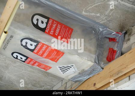 Avvertenza contiene amianto in inglese, tedesco e francese in un luogo di lavoro in cui l'amianto viene rimosso Foto Stock