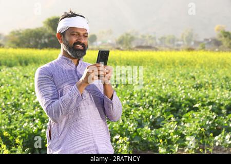 Felice agricoltore indiano che sente il vento mentre si stende il campo allungando le braccia. Foto Stock