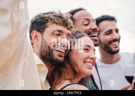 Incontro di un gruppo sorridente di persone che festeggia una festa, si diverte e si gode il momento insieme. Giovani amici, uomini e donne allegri ed eccitati che si divertono a un festival. Allegri amici che si riuniscono. Foto di alta qualità Foto Stock