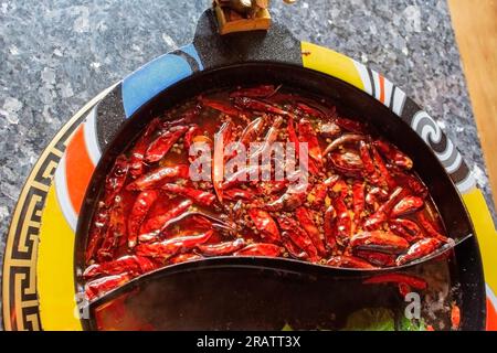 Vista dall'alto di una parte della zuppa di peperoncino molto piccante in una pentola calda. Un tavolo con deliziosi piatti caldi. Foto Stock