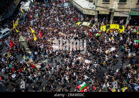 Jenin, Palestina. 5 luglio 2023. I luttuosi portano i corpi di uomini palestinesi, alcuni dei quali rivestiti dalle bandiere del gruppo militante della Jihad islamica e Hamas durante i loro funerali, nel campo profughi di Jenin, in Cisgiordania. L'esercito israeliano afferma di aver ritirato le proprie truppe dal campo mercoledì, ponendo fine a un'intensa operazione di due giorni che ha ucciso almeno 13 palestinesi, ha allontanato migliaia di persone dalle loro case e ha lasciato un'ampia serie di danni sulla scia. Anche un soldato israeliano è stato ucciso. Credito: SOPA Images Limited/Alamy Live News Foto Stock