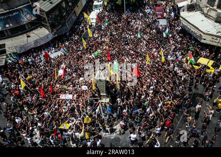 Jenin, Palestina. 5 luglio 2023. I luttuosi portano i corpi di uomini palestinesi, alcuni dei quali rivestiti dalle bandiere del gruppo militante della Jihad islamica e Hamas durante i loro funerali, nel campo profughi di Jenin, in Cisgiordania. L'esercito israeliano afferma di aver ritirato le proprie truppe dal campo mercoledì, ponendo fine a un'intensa operazione di due giorni che ha ucciso almeno 13 palestinesi, ha allontanato migliaia di persone dalle loro case e ha lasciato un'ampia serie di danni sulla scia. Anche un soldato israeliano è stato ucciso. Credito: SOPA Images Limited/Alamy Live News Foto Stock