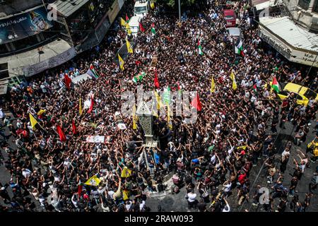 Jenin, Palestina. 5 luglio 2023. I luttuosi portano i corpi di uomini palestinesi, alcuni dei quali rivestiti dalle bandiere del gruppo militante della Jihad islamica e Hamas durante i loro funerali, nel campo profughi di Jenin, in Cisgiordania. L'esercito israeliano afferma di aver ritirato le proprie truppe dal campo mercoledì, ponendo fine a un'intensa operazione di due giorni che ha ucciso almeno 13 palestinesi, ha allontanato migliaia di persone dalle loro case e ha lasciato un'ampia serie di danni sulla scia. Anche un soldato israeliano è stato ucciso. (Foto di Nasser Ishtayeh/SOPA Images/Sipa USA) credito: SIPA USA/Alamy Live News Foto Stock