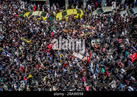 Jenin, Palestina. 5 luglio 2023. I luttuosi portano i corpi di uomini palestinesi, alcuni dei quali rivestiti dalle bandiere del gruppo militante della Jihad islamica e Hamas durante i loro funerali, nel campo profughi di Jenin, in Cisgiordania. L'esercito israeliano afferma di aver ritirato le proprie truppe dal campo mercoledì, ponendo fine a un'intensa operazione di due giorni che ha ucciso almeno 13 palestinesi, ha allontanato migliaia di persone dalle loro case e ha lasciato un'ampia serie di danni sulla scia. Anche un soldato israeliano è stato ucciso. (Foto di Nasser Ishtayeh/SOPA Images/Sipa USA) credito: SIPA USA/Alamy Live News Foto Stock