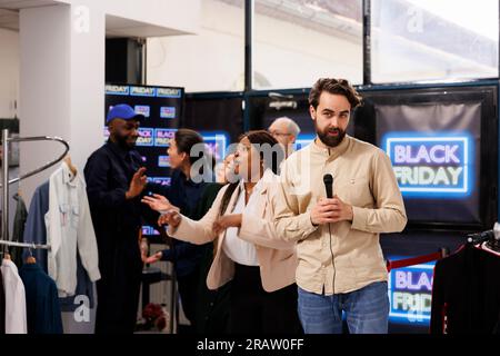 Entusiasta folla di acquirenti che si affrettano a raggiungere il negozio di abbigliamento per ottenere le migliori offerte. Follia e frenesia persone diverse che si imbattono in un centro commerciale durante le vendite del Black Friday, in cerca di occasioni Foto Stock