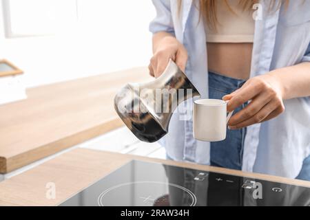 Donna che versa caffè fresco dalla jezve nella tazza in cucina Foto Stock