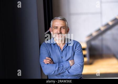 Uomo di mezza età barbuto che indossa occhiali che guarda la fotocamera con un'espressione seria in un ritratto ravvicinato della testa e delle spalle Foto Stock