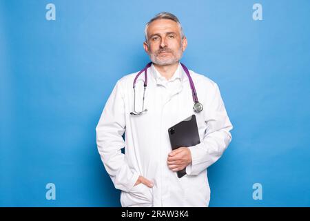 Uomo di mezza età amico in abito bianco che indossa occhiali con stethocsope sul suo medico del petto che regge una tavoletta digitale Foto Stock