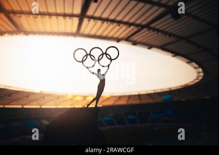 PARIGI, FRANCIA, 7 LUGLIO 2023: Potere simbolico: Statua della donna atletica solleva il cerchio olimpico al moderno Stadio Olimpico. Foto sportiva per Parigi 2024 Summ Foto Stock