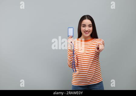 Happy Woman con badge vip pass su sfondo grigio. Spazio per il testo Foto Stock