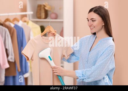 Donna che fuma la camicia su un appendiabiti a casa Foto Stock