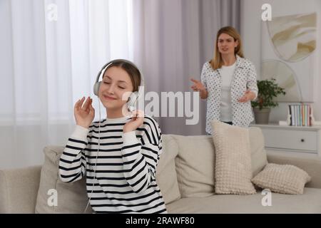 Figlia adolescente con le cuffie che ignora sua madre a casa Foto Stock