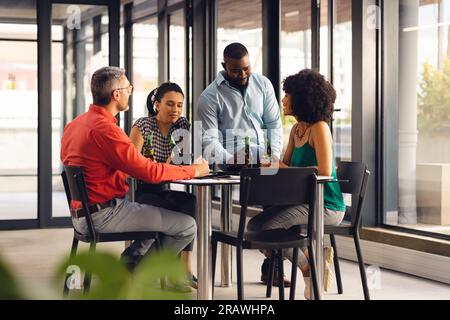 Felici e diversi colleghi informali che parlano e bevono birre in ufficio. Affari occasionali, lavoro di squadra, legame, successo e festeggiamenti, inalterati. Foto Stock
