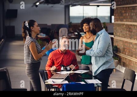 Felice e diversificato colleghi di lavoro informali che parlano durante una riunione d'ufficio. Affari occasionali, lavoro di squadra, riunioni, comunicazione e lavoro, inalterati. Foto Stock