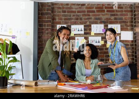 Ritratto di stilisti felici e diversi durante la riunione di design in studio. Business, lavoro di squadra, comunicazione, riunione, brainstorming, moda e design Foto Stock